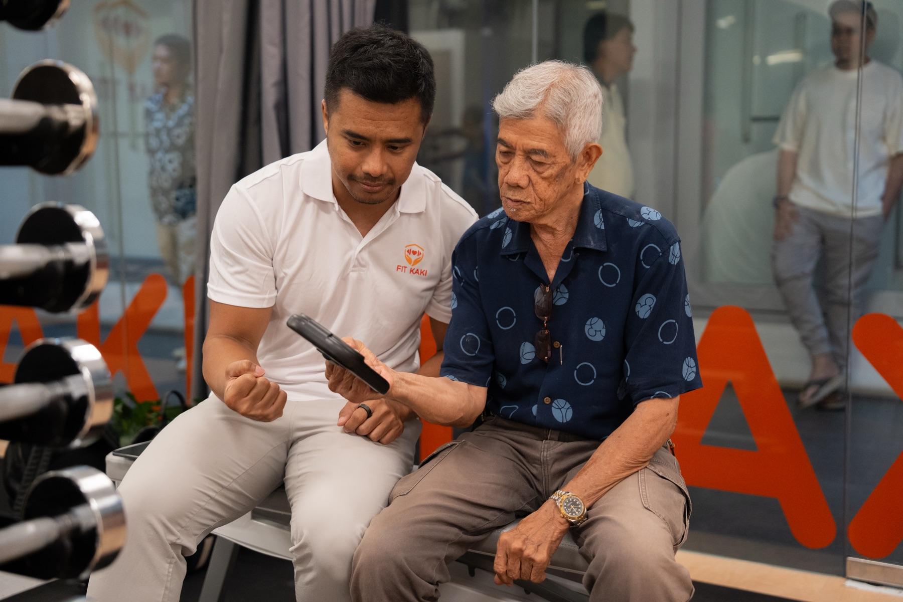 A Fit Kaki coach and a senior man looking through his results together outside the studio, both at ease